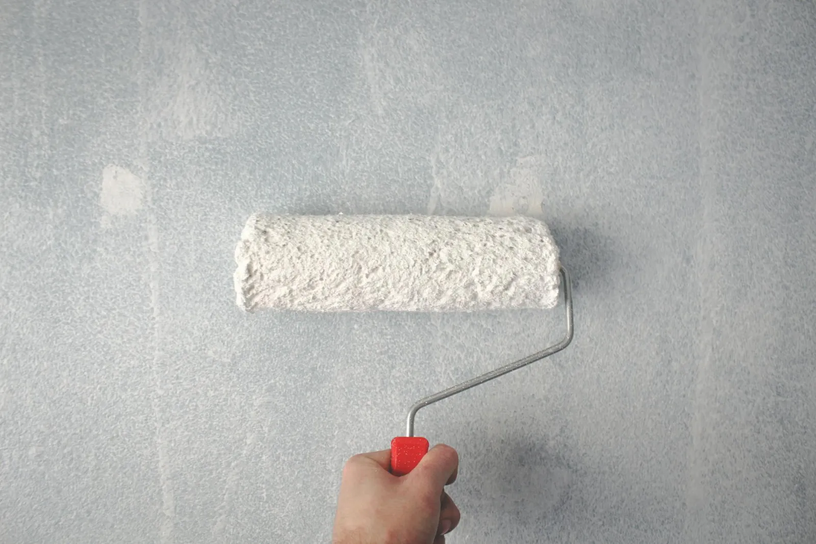 Paint roller applying fresh coat to condo wall
