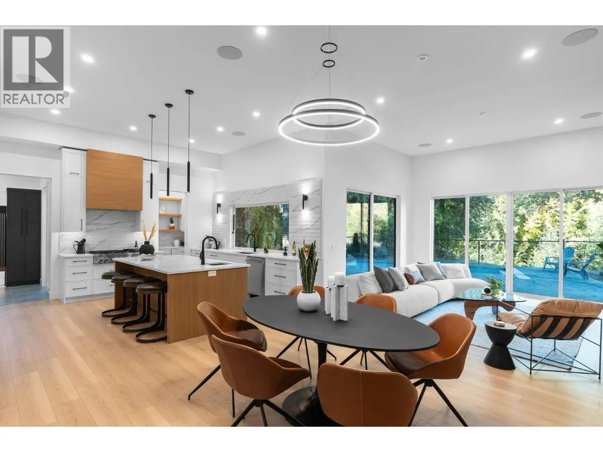 4630 McClure Road open concept kitchen, dining and living area with modern ring chandelier and pool views